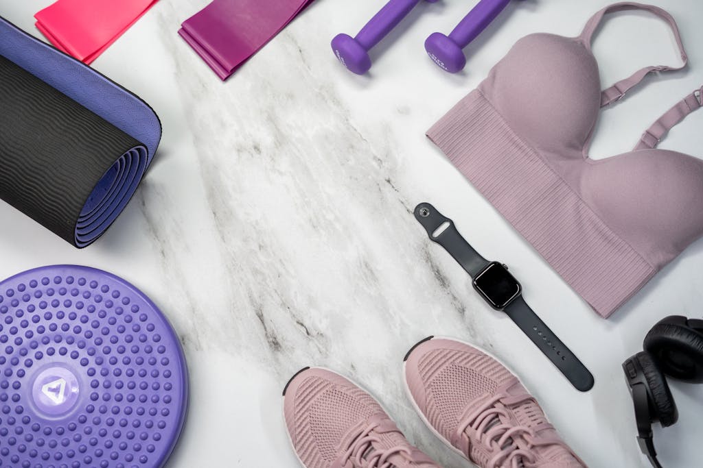 Top view of fitness equipment including smartwatch, bra, sneakers, and more on marble