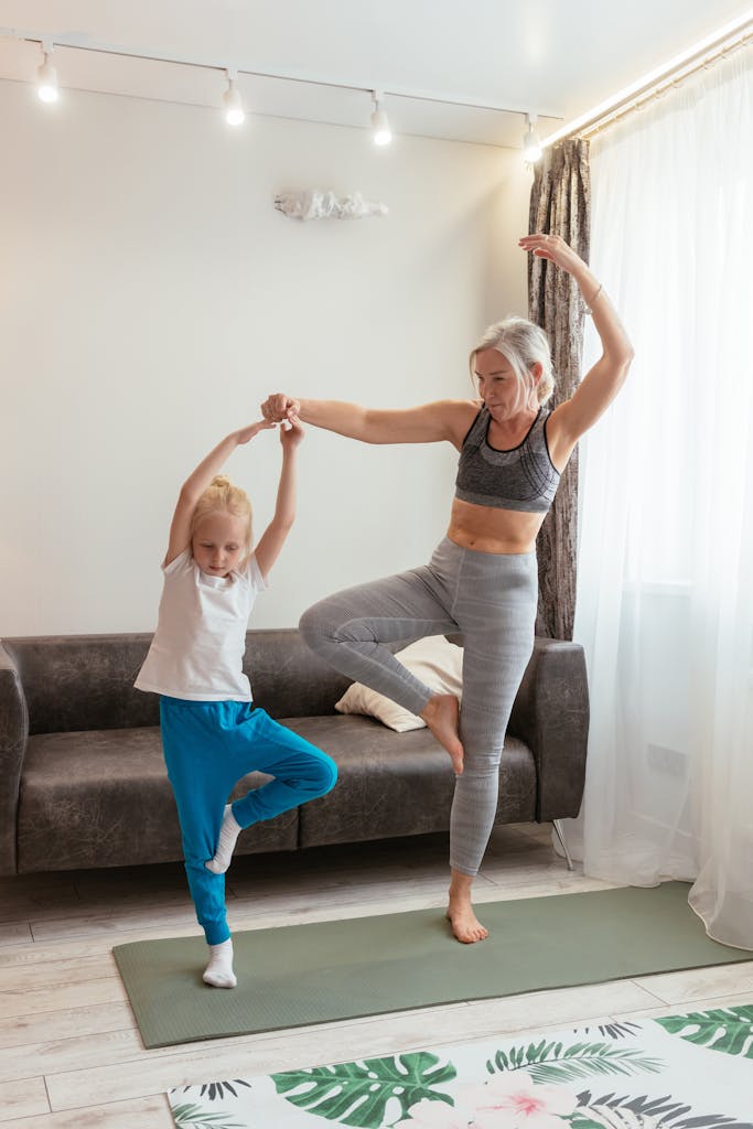 A senior woman and young girl enjoy yoga in a cozy living room.